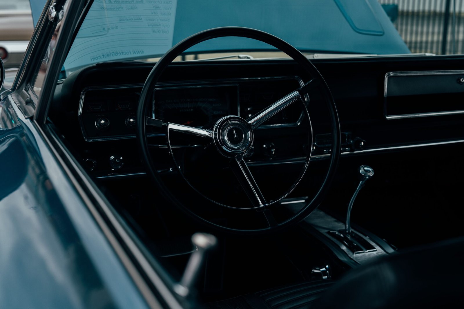 Vintage car interior featuring a classic steering wheel and dashboard in moody lighting.
