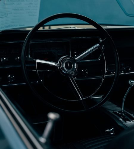 About Vintage car interior featuring a classic steering wheel and dashboard in moody lighting.