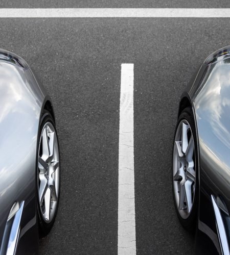 About Two silver cars parked symmetrically in an outdoor lot.